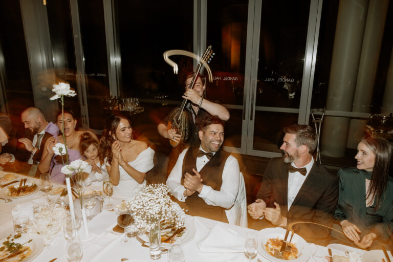 Candid shot at a wedding event with people enjoying food and music at the dining table - wedding DJ Canberra, 8 til late