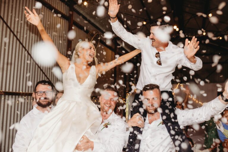 Wedding couple lifted on shoulders by friends, joyfully celebrating during the wedding ceremony - wedding DJ Canberra