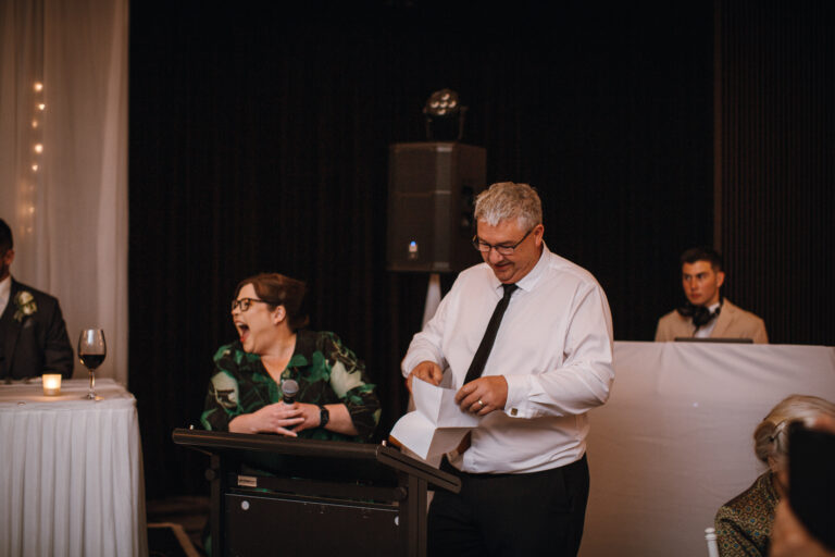 Elderly man at a wedding event holding a paper, appearing to announce something to the audience - wedding DJ Canberra