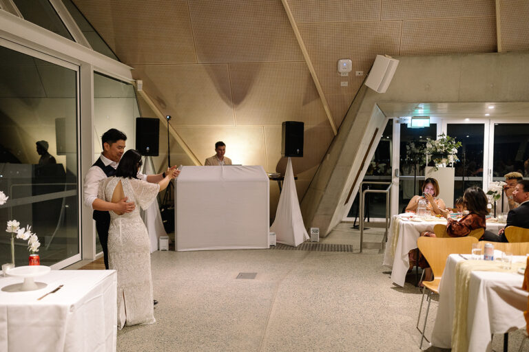 People sitting in an event with a DJ making the music and a wedding couple is having a couple dance - wedding dj canberra