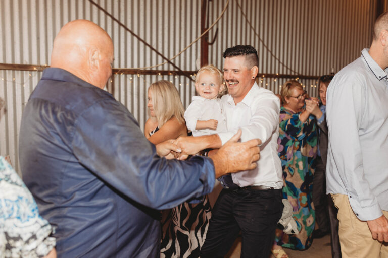 Happy man joyfully holding a child, enjoying the dance in a wedding event with another man - wedding DJ Canberra, 8 til late