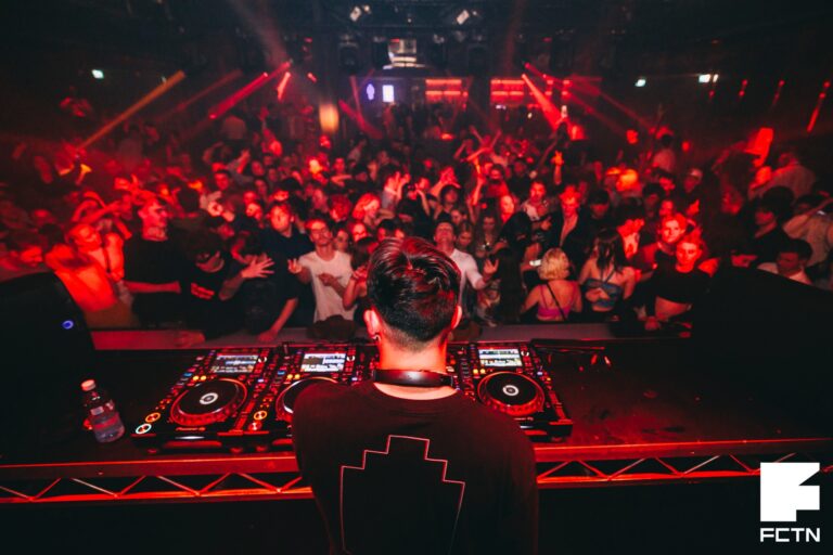 Back shot of a DJ with a DJ system in a nightclub event, crowd in front, red lighting theme - Canberra DJ hire, 8 til late